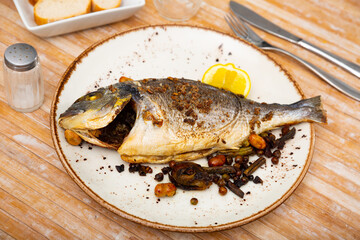 Appetizing roasted dorada served with stewed eggplant and bell pepper garnished