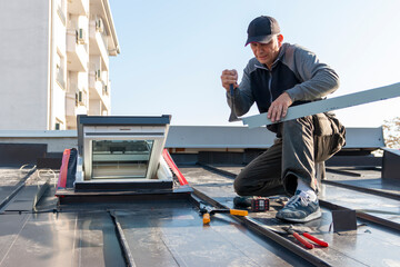 A roofer builder worker finishing folding a metal sheet using special pliers with a large flat...