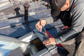 A roofer builder worker finishing folding a metal sheet using special pliers with a large flat grip. A roofer and window master work.  House improvement under construction concept