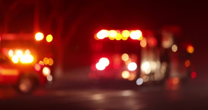 Abstracted bokeh view of fire, police, and emergency medical ambulance assets arriving on scene at night.