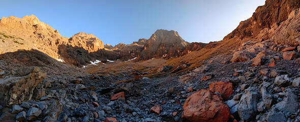 Panoramic view of mountains at sunrise, during the summer, with a sunset in red and orange tones
