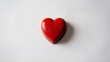 Red Heart-Shaped Chocolate: A simple yet striking photo of a single, perfectly shaped red heart-shaped chocolate captured from a top-down angle on a smooth white background