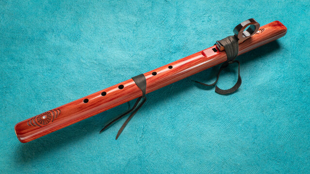 native American style flute handcrafted from aromatic cedar wood against art paper
