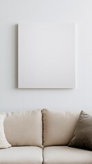 Minimalist interior design featuring a large blank canvas on a white wall above a cozy beige sofa with cushions, creating a stylish living room atmosphere
