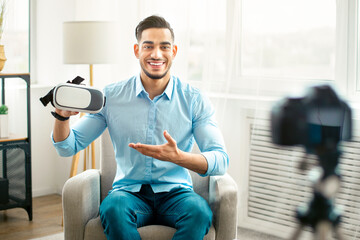 Arab guy vlogger making tech product review, presenting VR headset, shooting video about cool...