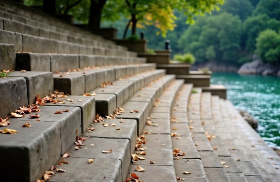 Autumnal scene shows concrete staircase leading down to river. Leaves trash steps. Riverside promenade cobblestone paving, wooden benches. Serene urban setting. Perfect for park design, landscaping, - Powered by Adobe