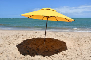 Yellow umbrella on the beach with the sea in the background. Itacimirim, Bahia-Brazil