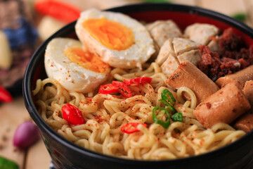 Boiled noodles with egg, sausage, corned beef, meatballs, chili served in a bowl. Boiled noodles are a favorite food of Asian people. boiled noodles delicious food