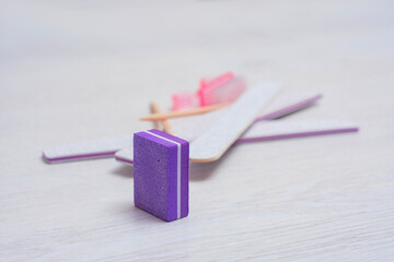 Manicure kit featuring nail files, buffer, sticks, and a brush on a light wooden background.