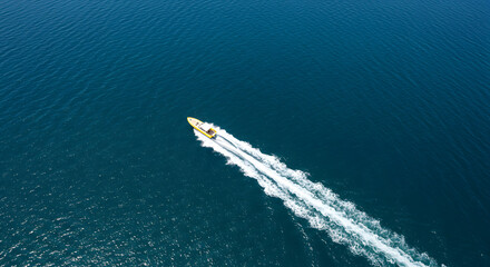 A top-down image depicting a swift motorboat moving across the expansive surface of the open sea.