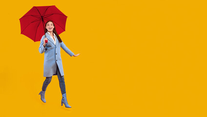 Happiness Concept. Full length of excited lady walking with yellow umbrella, isolated over pink...