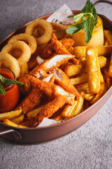 A plate of fish and chips with french fries, ketchup, mustard, and delicious sauces on a white background