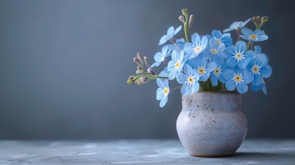 A delicate arrangement of blue flowers in a simple ceramic vase on a soft background.