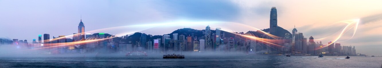 Fototapeta premium Misty Hong Kong skyline at dawn, city skyscrapers shrouded in fog, with streaks of light suggesting movement.