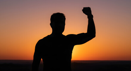 Fototapeta premium A silhouette of a committed individual, fist uplifted in success, emerges against a shining backdrop.