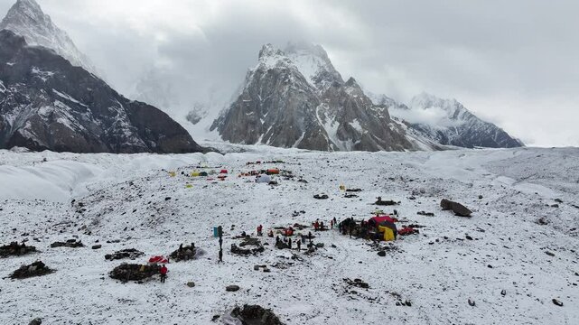 Drone footage flying over a snowy landscape and campsite in Pakistan among the Karakoram Mountains, captured while trekking to K2 Base Camp.