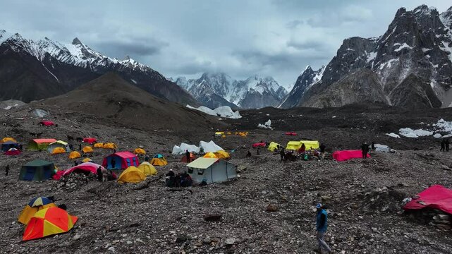 Aerial drone footage in Pakistan panning over a hiking tent and camp setup among the Karakoram Mountains, captured while trekking to K2 Base Camp.