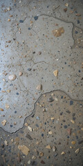 Close-up of a textured concrete surface with stones and cracks.