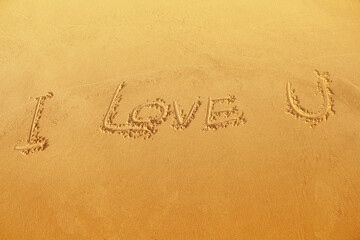 I Love You Symbol written on sand beach light brown top view background