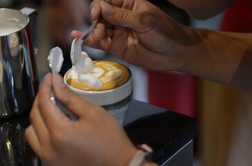 barista's hand creating foam art using spoon
