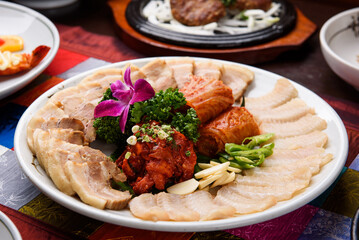 Dried fermented skate, boiled pork, and kimchi served on a white round plate