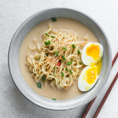 Overhead view of milky ramen, top view of milk ramen in a grey bowl, trendy creamy ramen noodles