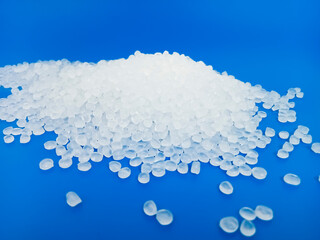 PP plastic pellets, virgin polypropylene polymer plastic granules poured into blue background, for...