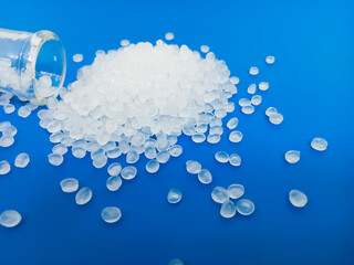 PP plastic pellets, virgin polypropylene polymer plastic granules poured into blue background, for...