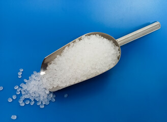 PP plastic pellets, virgin polypropylene polymer plastic granules poured from scopp into blue background, for product catalog design of plastic manufacturing industry company profile