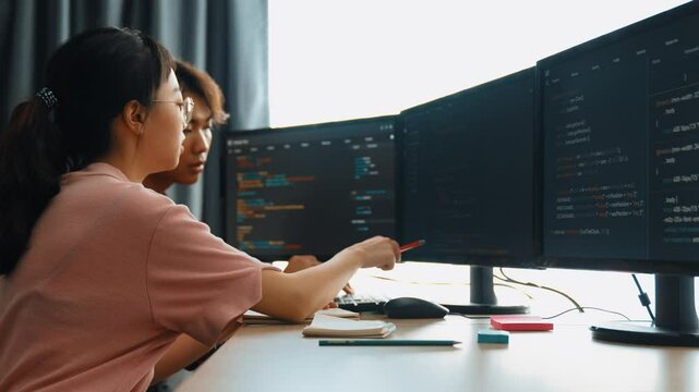 Slow motion back end software developer engineer for computer programming working together on debugging writing computing code, solving complex algorithms display on monitor in office. Burgeoning