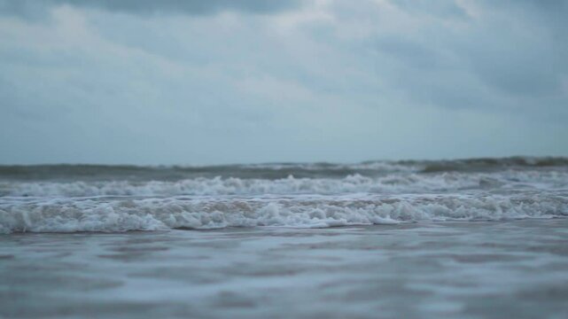 Close up shot of frothy sea waves crashing on sandy beach at Mandvi, Kutch, India. Slow motion video of waves water. Tropical beach close up slow motion video
