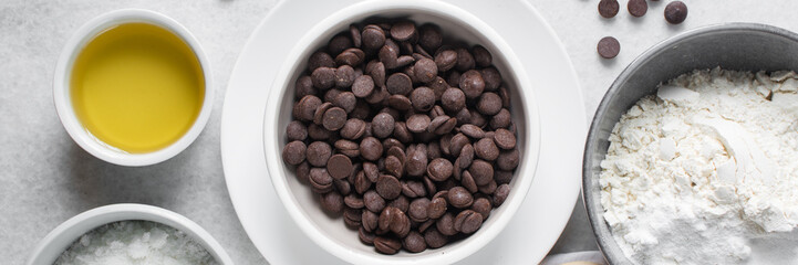overhead view of mise en place for homemade chocolate chip cookies, ingredients for making chocolate chip cookies on a marble countertop	