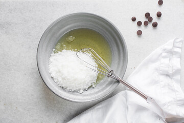 Creaming oil and sugar in a grey bowl with a whisk, the process of making a cake and cookies, mixing oil and sugar to make a cake and cookies