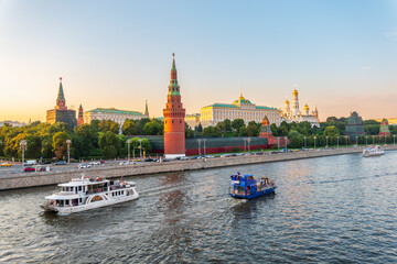 View of Kremlin with Vodovzvodnaya tower, Grand Kremlin Palace from repaired Bolshoy Kamenny Bridge in Moscow city on sunny summer day. Cruise ship sails on the Moscow river