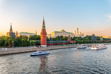 Obraz premium View of Kremlin with Vodovzvodnaya tower, Grand Kremlin Palace from repaired Bolshoy Kamenny Bridge in Moscow city on sunny summer day. Cruise ship sails on the Moscow river