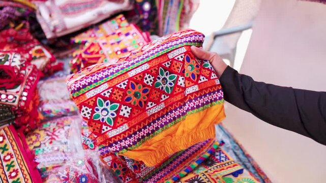 Close up shot of woman buying handicraft clothes from Rann Utsav market in Kutch, Gujarat, India. Beautiful Kutchi Handicraft arctician designer cloth in local street market. Shopping concept. 