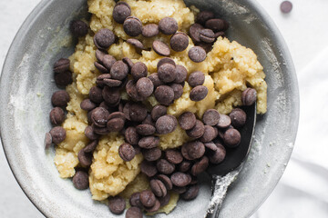 Overhead view of chocolate chip cookie dough, top view of homemade chocolate chip cookie dough in a bowl on a white background, process of making chocolate chip cookies