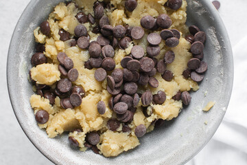 Overhead view of chocolate chip cookie dough, top view of homemade chocolate chip cookie dough in a bowl on a white background, process of making chocolate chip cookies