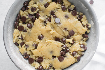 Overhead view of chocolate chip cookie dough, top view of homemade chocolate chip cookie dough in a bowl on a white background, process of making chocolate chip cookies