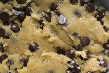 Overhead view of chocolate chip cookie dough, top view of homemade chocolate chip cookie dough in a bowl on a white background, process of making chocolate chip cookies