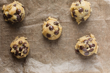 Overhead view of chocolate chip cookie dough being scooped onto a baking sheet, top view of homemade chocolate chip cookie dough, process of making chocolate chip cookies
