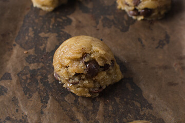 scoops of chocolate chip cookie dough on a baking sheet, homemade chocolate chip cookie dough, process of making chocolate chip cookies