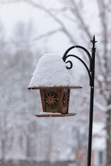 Snow covered birdfeeder on black iron hook