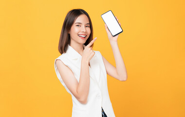 Naklejka premium Beautiful Asian woman holding smartphone mockup of blank screen and smiling on yellow background.