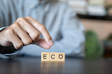 ECO concept. Business man hand holding wooden cube words ECO on a wood block