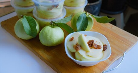 Freshly sliced guava with leaves on a wooden board, ideal for healthy eating and natural lifestyle themes.
