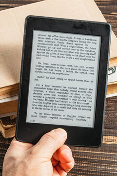 Reading an electronic book on a wooden table near the window during the day