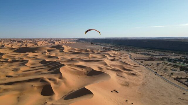 A paramotor flight over the stunning Taghit Desert in southern Algeria. Experience breathtaking aerial views of endless golden sand dunes as the camera follows the soaring journey.