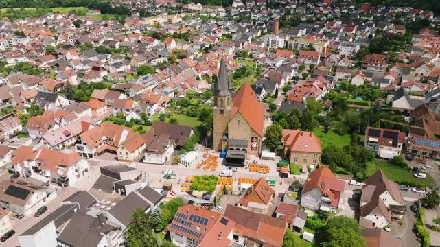 Beautiful Rauenberg town traditional red roof houses with Catholic church building in center, Saint Peter and Paul Church facade, Europe, Establishing drone shot