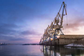 River or sea cargo cranes on the pier in the morning at dawn copyspace . Cargo transportation and logistics